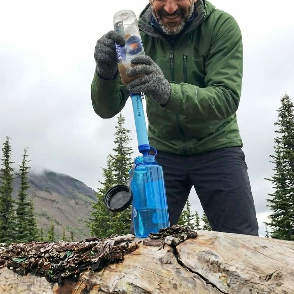 Hiker filtering mountain water into a bottle